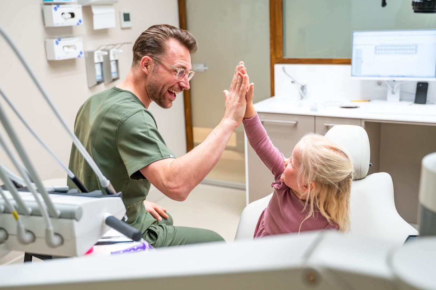 Tandarts geeft een kind een high five na de controle